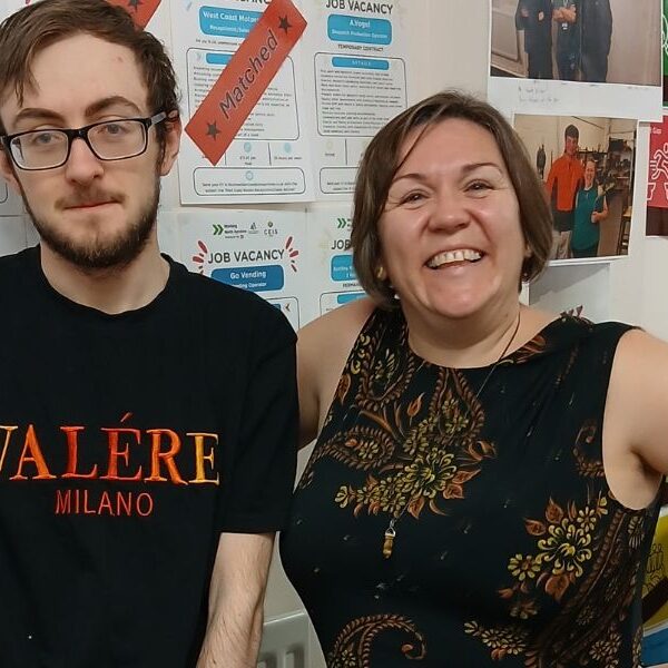 Man and Woman standing in front of a wall. Job vacancies can be seen attached to the wall. Some with a red label that reads "matched"