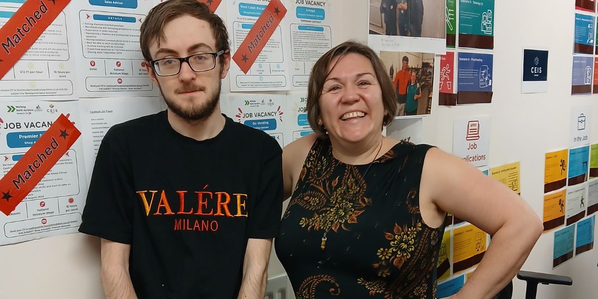 Man and Woman standing in front of a wall. Job vacancies can be seen attached to the wall. Some with a red label that reads "matched"